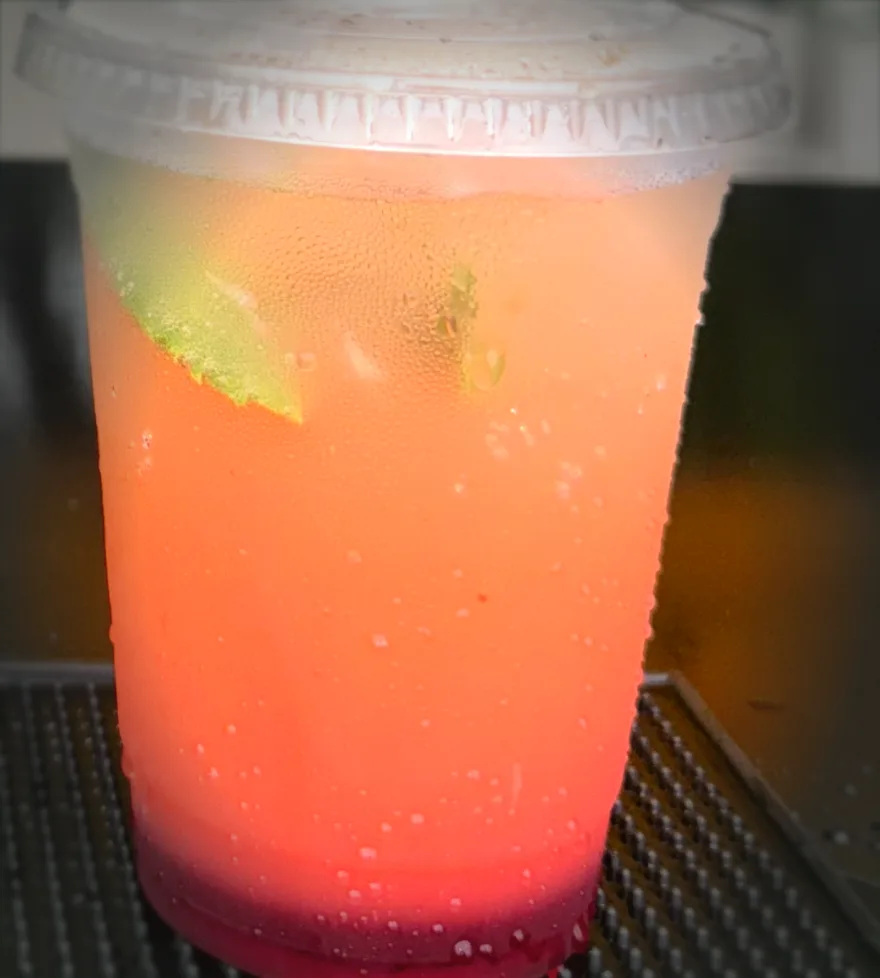 Tropical Sunrise — a peach-and-pink layered iced mocktail in a clear cup